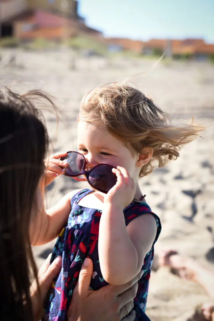 petite fille blonde à la plage essaie les lunettes de sa maman
