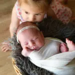 photo nouveau-né panier fourrure grise emmaillotement blanc bisou bébé grande soeur