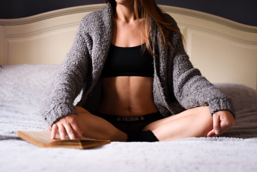 femme en posture de yoga sur un lit gilet gris