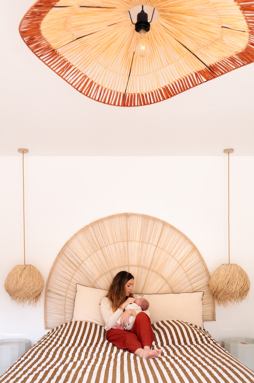 photo graphique d'une maman avec son nouveau-né dans les bras sur le lit dans la chambre parentale lors d'une séance bébé par LONOWAÏ Photographie à narbonne