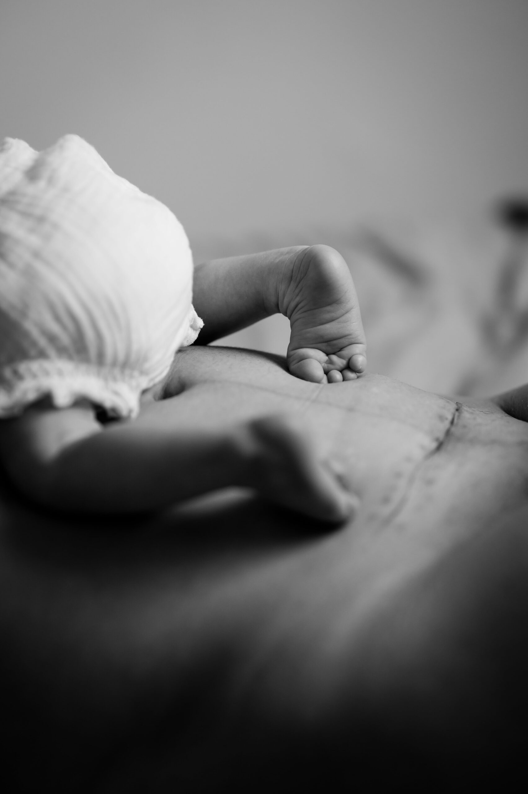 photo de pieds d'un nouveau-né sur le ventre de sa maman avec la cicatrice de la césarienne visible. Photo prise lors d'une séance de maternité intimiste par LONOWAÏ Photographie à Narbonne