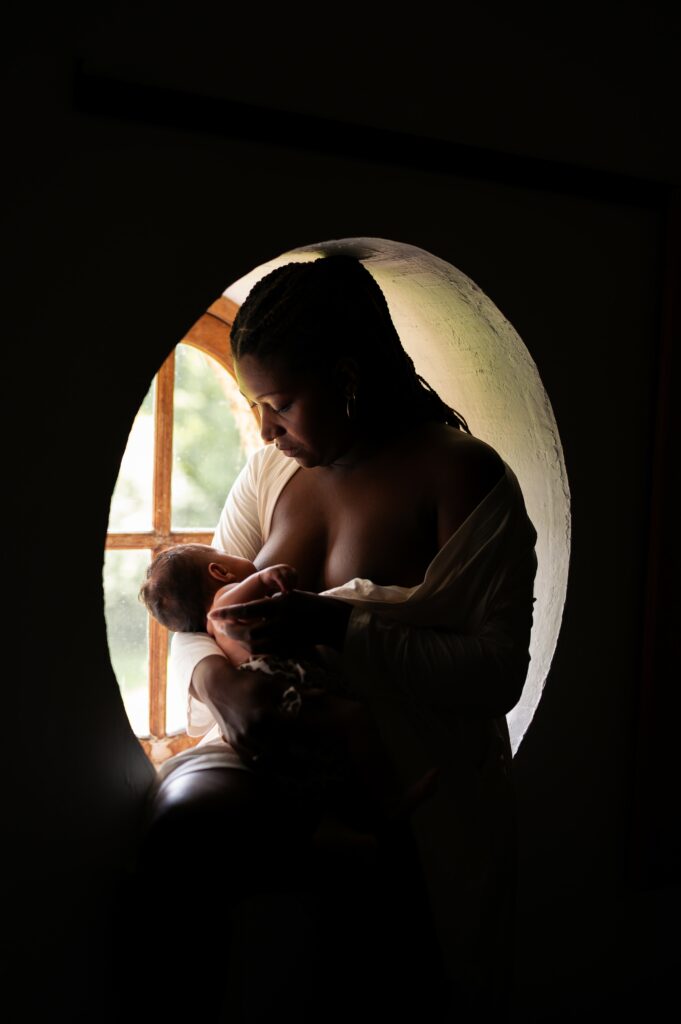 photo d'une femme allaitant son bébé nouveau-né dans l'encadrement rond d'une fenêtre. Phoot prise lors d'une séance de maternité intimiste par LONOWAÏ Photographie à Narbonne
